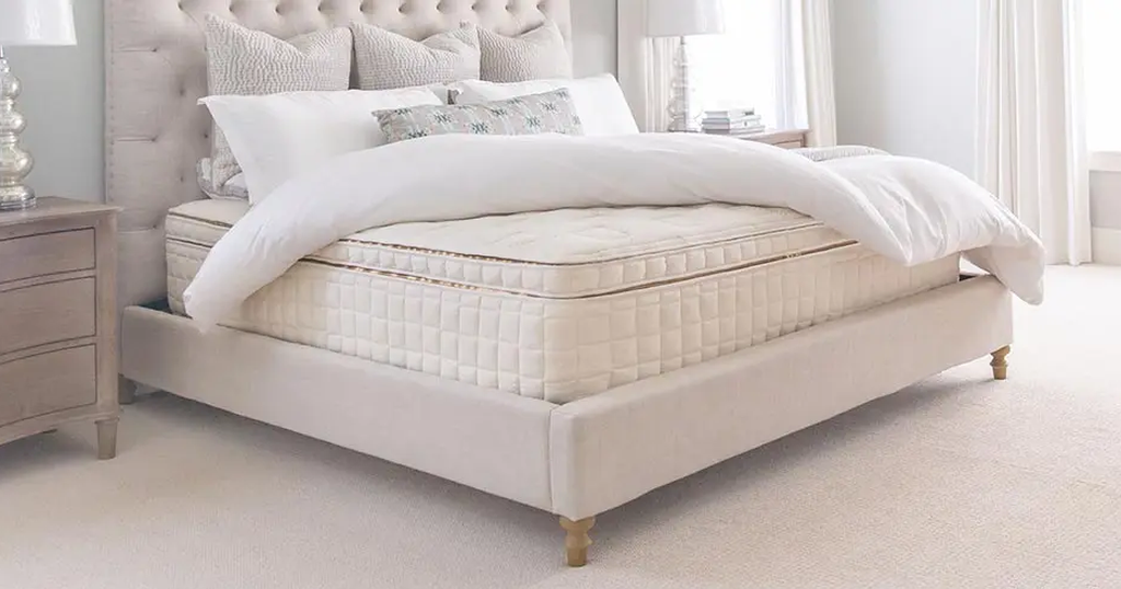 Eggshell colored Naturepedic EOS Pillow Top mattress with a folded over comforter on top and seven pillows